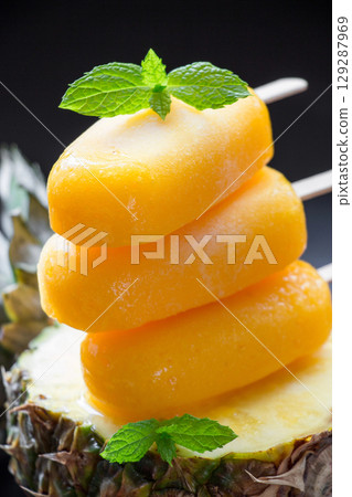 Delight in three vibrant mango pineapple ice cream scoops artfully arranged on a fresh pineapple slice. Each scoop is topped with a touch of mint for a refreshing appeal. Delight in three vibrant mango pineapple ice cream scoops artfully arranged on a fresh pineapple slice. Each scoop is topped with a touch of mint for a refreshing appeal. 129287969