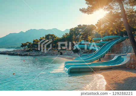 Aquapark with blue water slides on the sandy coast. 129288221