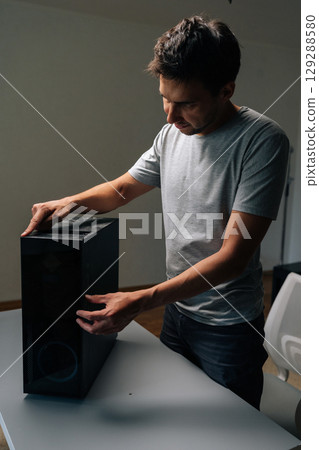 Vertical portrait of technician checking dust level on computer case, highlighting need for cleaning and maintenance to prevent overheating and improve performance. Concept of service, cleaning PC. 129288580