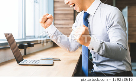 Smiling male businessman doing a fist pump Smiling male businessman doing a fist pump 129288616