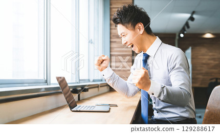 Smiling male businessman doing a fist pump Smiling male businessman doing a fist pump 129288617