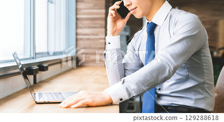 Smiling male businessman talking on a smartphone Smiling male businessman talking on a smartphone 129288618