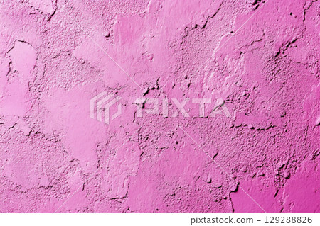 A close-up of a weathered, cracked wall with peeling paint, showing a textured surface in various shades of pink and light purple. 129288826