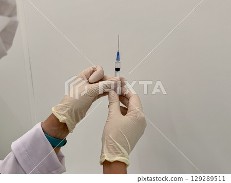 A medical officer in a white coat holds a syringe. Vaccination. High quality photo 129289511