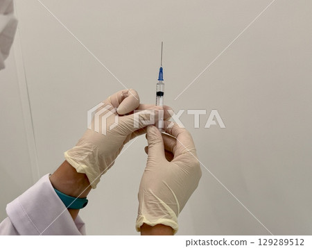 A medical officer in a white coat holds a syringe. Vaccination. High quality photo 129289512