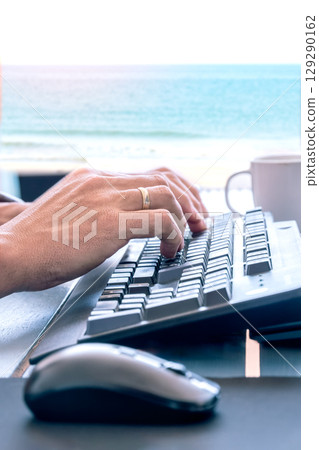 Remote work on keyboard with ocean view 129290162