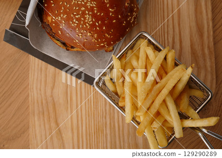 Top View Of Big Burger And Fried Potato In A Metal Wire Basket On A Wooden Board Top View Of Big Burger And Fried Potato In A Metal Wire Basket On A Wooden Board 129290289