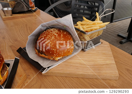 Classic serving of burger and fries on wooden board in a fast food restaurant Classic serving of burger and fries on wooden board in a fast food restaurant 129290293