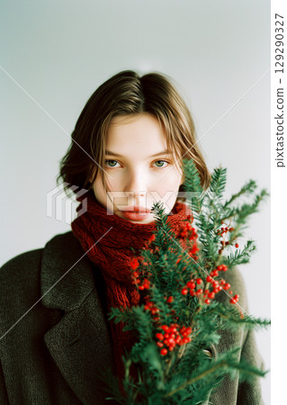 A woman is holding a Christmas tree with berries in her scarf 129290327