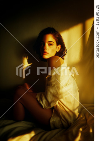 A woman is sitting on a bed with her arms crossed A woman is sitting on a bed with her arms crossed 129290329