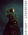 A woman wearing a plaid dress is holding a Christmas tree in her arms 129290344