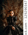 A woman with long hair is sitting in a chair wearing a black dress 129290347