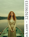 A woman in a gold dress is standing in a boat on a lake 129290353