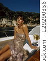 A woman in a gold dress is sitting on a boat in the water 129290356