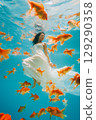 A woman is swimming in a pool with many goldfish 129290358