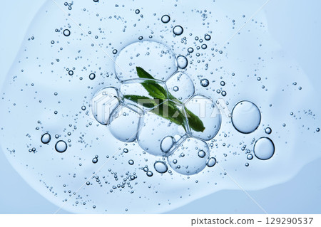 Beautiful texture of gel-like serum with a leaf on a blue background. 129290537