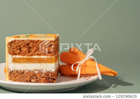 Bento cake featuring layers of moist carrot, vibrant orange, and sweet mango, beautifully presented on a white plate with fresh carrots, showcasing a delightful dessert experience 129290629