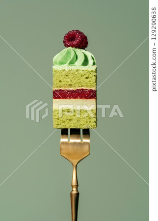 Layered bento cake featuring vibrant raspberry and pistachio sponge, topped with creamy frosting and a fresh raspberry, elegantly presented on a golden fork against a soft green background Layered bento cake featuring vibrant raspberry and pistachio sponge, topped with creamy frosting and a fresh raspberry, elegantly presented on a golden fork against a soft green background 129290638
