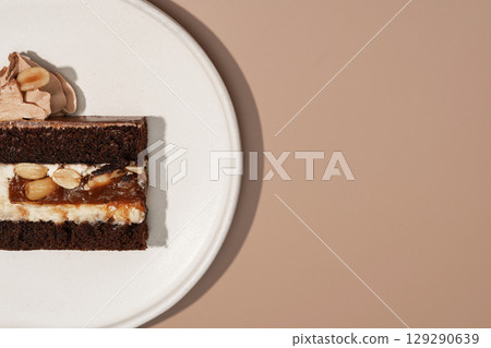 Decadent bento cake featuring rich chocolate sponge layered with caramel, nuts, and creamy frosting, beautifully presented on a white plate, perfect for dessert and pastry menu concepts 129290639