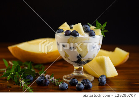 Refreshing yogurt dessert with melon and blueberries on a wooden 129290707