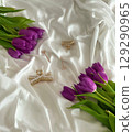 Purple tulips arranged on white satin fabric with elegant jewelry pieces, showcasing beauty and lifestyle themes. 129290965