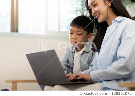 Remote Learning. Mother and son engaging with laptop for educational activities at home. 129291073