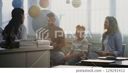 Mother and Father Looking at School Test Grades of Their Son During Parents Evening 129291412