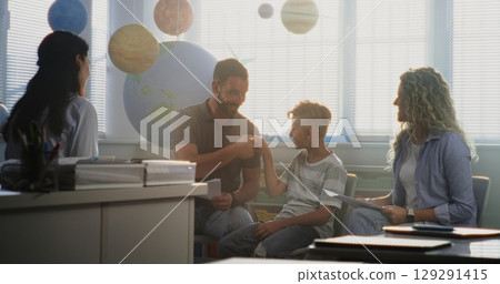 Mother and Father Looking at School Test Grades of Their Son During Parents Evening Mother and Father Looking at School Test Grades of Their Son During Parents Evening 129291415