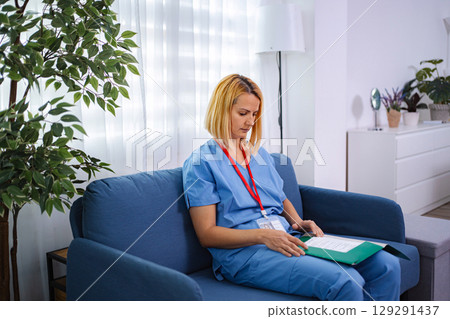 Female doctor reading patient's medical history at home 129291437
