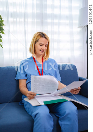 Female Doctor Reviewing Medical Records at Home 129291441