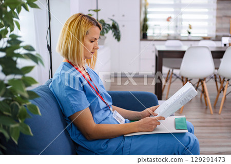 Young female doctor is reading medical records of her patient 129291473