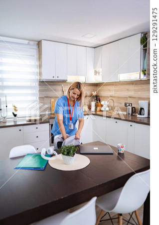 Female Doctor Preparing Her Backpack in the Kitchen Before Going to Work 129291475