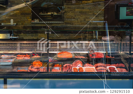 Display case with meat products. Assortment of fresh meat, sausages, and cuts displayed in glass counter at butcher shop. Concept of meat market, raw meat, protein selection 129291510