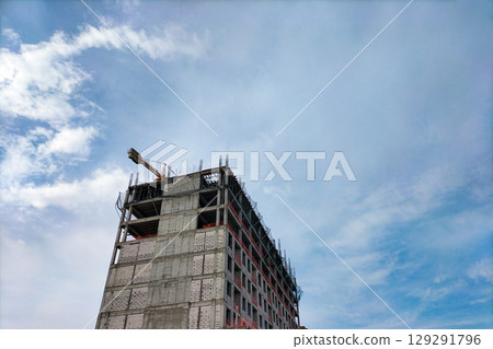 Construction of multi-story building with load-bearing frame made of monolithic reinforced concrete and gas blocks walls. Special protective nets stretched to prevent workers and objects from falling 129291796