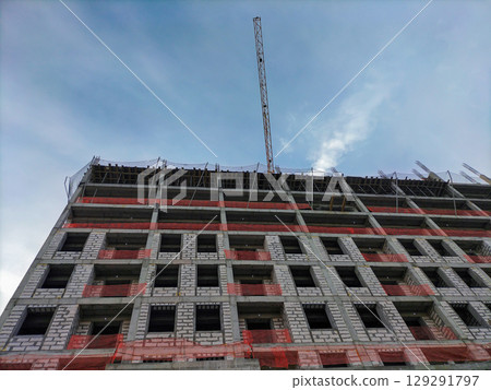 View from below of construction of multi-story building with load-bearing monolithic reinforced concrete frame, gas blocks walls. Special protective nets stretched to prevent workers from falling View from below of construction of multi-story building with load-bearing monolithic reinforced concrete frame, gas blocks walls. Special protective nets stretched to prevent workers from falling 129291797