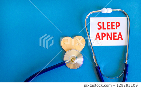 Sleep apnea symbol. Concept words Sleep apnea on beautiful white card. Wooden heart and stethoscope. Beautiful blue background. Medical healthy lifestyle sleep apnea concept. 129293109