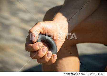Sports black rubber expander in man's hand. 129293163