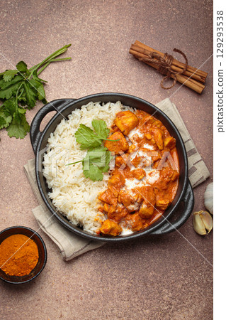 Indian dish chicken tikka masala served with rice and spices on beige background top view 129293538