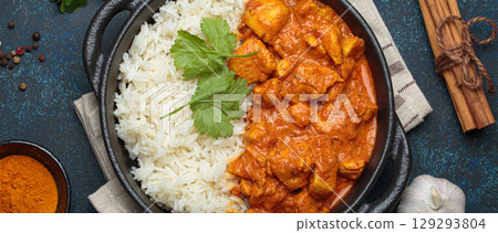 Indian dish chicken tikka masala served with rice and spices on dark blue background top view 129293804