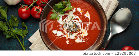 Tomato soup with cream, pumpkin seeds and herbs on blue background top view Tomato soup with cream, pumpkin seeds and herbs on blue background top view 129293808
