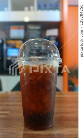 Iced Coffee in a Clear Plastic Cup on a Wooden Table 129294250