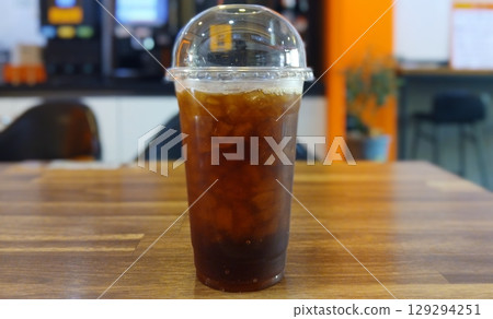 Iced Coffee in a Clear Plastic Cup on a Wooden Table 129294251