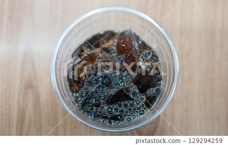 Top View of Iced Coffee in a Plastic Cup on a Wooden Table Top View of Iced Coffee in a Plastic Cup on a Wooden Table 129294259