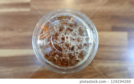 Top View of Iced Coffee in a Plastic Cup on a Wooden Table 129294260