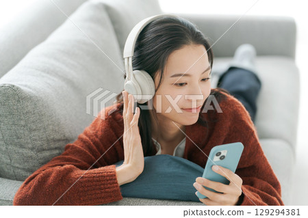 A young woman listening to music with headphones 129294381