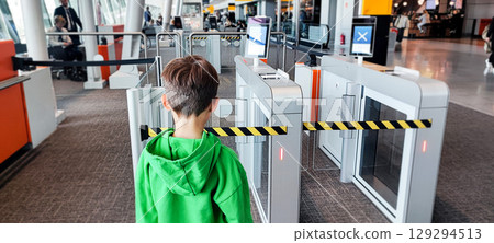 A toddler boy waits at the electronic gates of the airport. A modern concept of travel security and biometric control. A toddler boy waits at the electronic gates of the airport. A modern concept of travel security and biometric control. 129294513