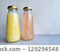 Two bottles of pink and yellow drinks with metal lids 129294548
