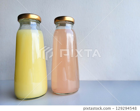 Two bottles of pink and yellow drinks with metal lids Two bottles of pink and yellow drinks with metal lids 129294548