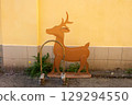 A small brown deer is standing outside in front of a house wall. New Year's concept 129294550