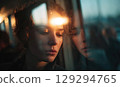 Young European woman leaning her forehead on the window of a train, blurring cityscape at sunset. 129294765
